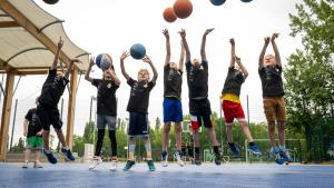 Kinder springen hoch und werfen Basketbälle in die Luft